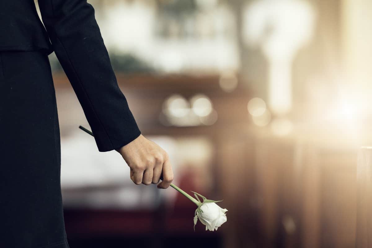 main qui tient une rose blanche à un enterrement pour Obtenir un acte de décès